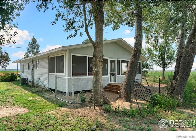 view of front of property with central AC, a front lawn, and a sunroom