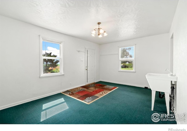 carpeted entryway featuring baseboards and an inviting chandelier