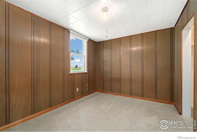 unfurnished room featuring light carpet and wooden walls