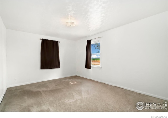 empty room featuring carpet floors and baseboards