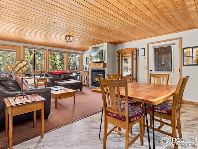 dining space with wooden ceiling and a glass covered fireplace