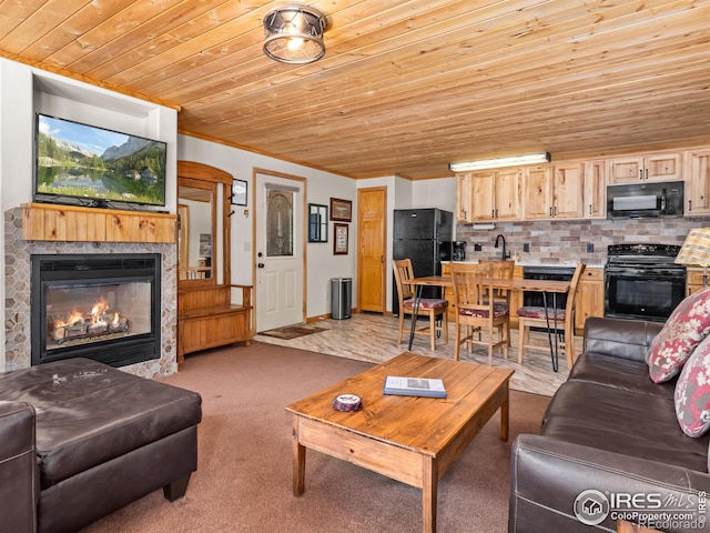 living area featuring a glass covered fireplace, wooden ceiling, light colored carpet, and crown molding