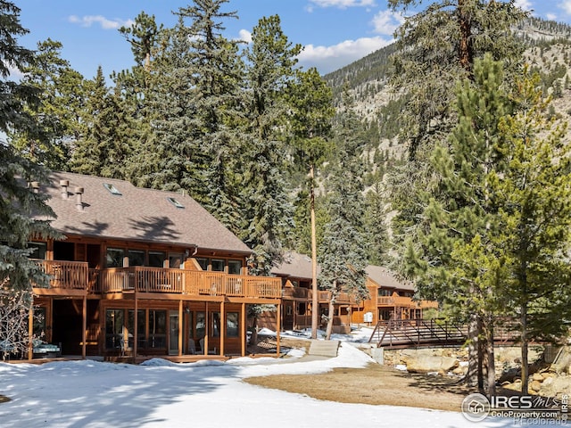 view of front of house featuring roof with shingles and a deck with mountain view