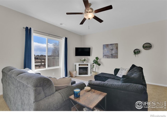 living area with a fireplace, visible vents, a ceiling fan, light carpet, and baseboards