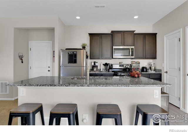 kitchen with visible vents, a breakfast bar area, stainless steel appliances, and dark brown cabinets