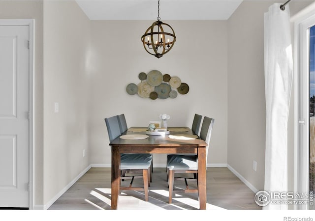 dining space featuring an inviting chandelier, light wood-style flooring, and baseboards