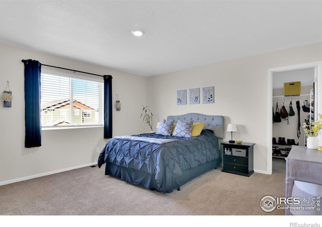 carpeted bedroom with a spacious closet and baseboards