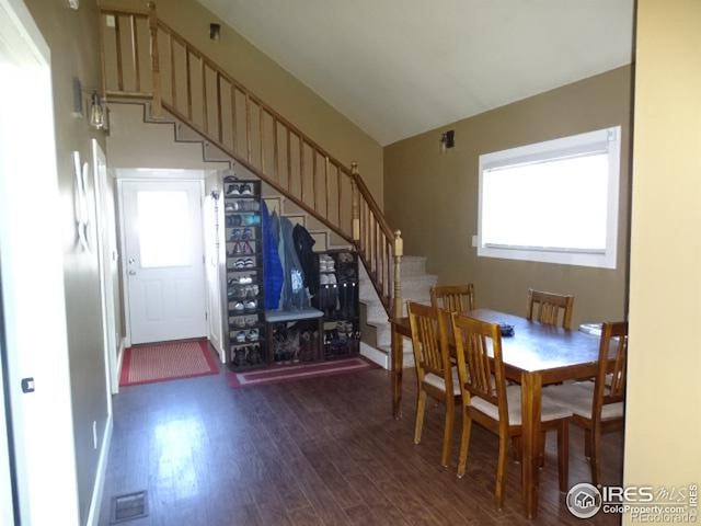 dining room with lofted ceiling, stairway, and dark wood-type flooring