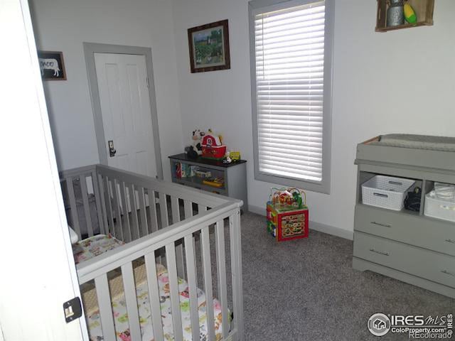 bedroom featuring carpet, multiple windows, a crib, and baseboards