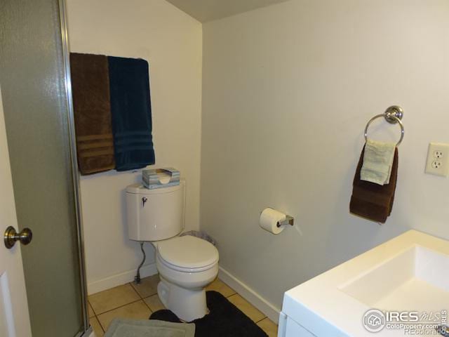 bathroom featuring toilet, a shower with shower door, baseboards, and tile patterned floors