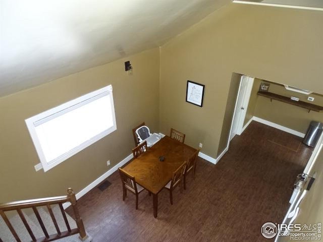 dining room featuring lofted ceiling, dark wood-type flooring, and baseboards