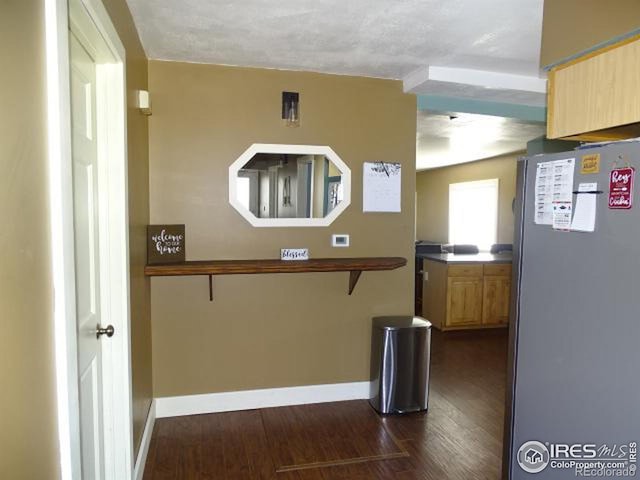 kitchen with light brown cabinets, baseboards, dark wood finished floors, and freestanding refrigerator