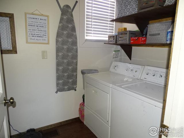 laundry room featuring dark wood-style floors, washer and dryer, laundry area, and baseboards