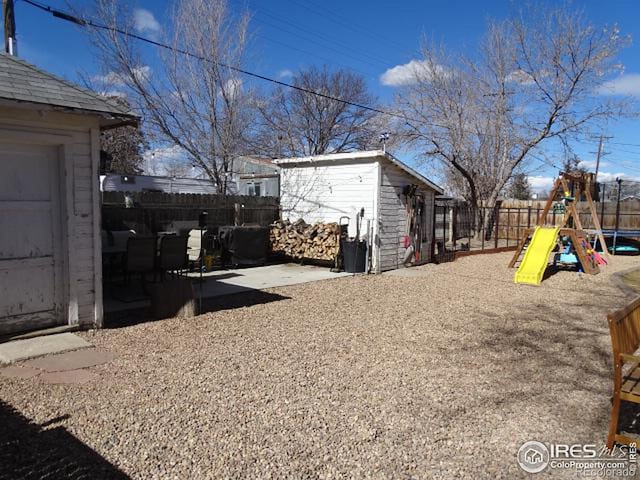 view of yard with an outbuilding, a playground, a fenced backyard, and a storage shed