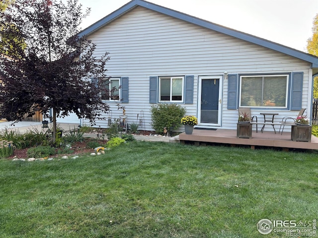 back of house with a deck and a lawn