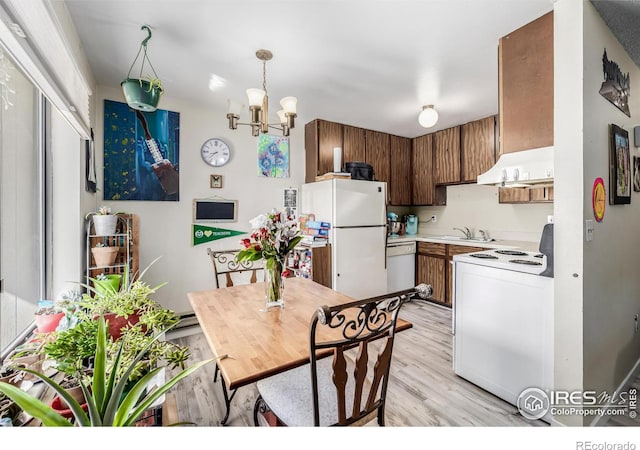 kitchen with a notable chandelier, light countertops, light wood-style flooring, a sink, and white appliances