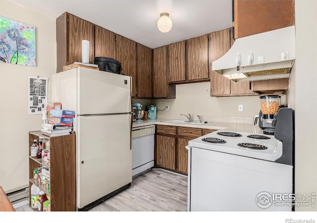 kitchen featuring white appliances, light wood-style floors, light countertops, under cabinet range hood, and a sink