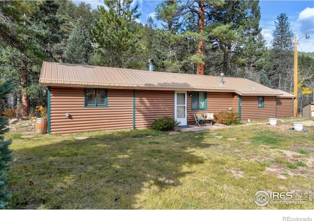 back of house with metal roof, a lawn, and log veneer siding