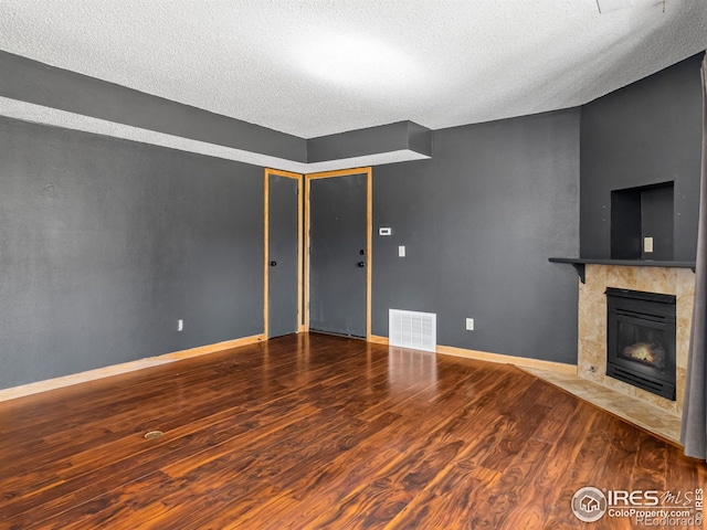 unfurnished living room featuring visible vents, a fireplace, baseboards, and wood finished floors