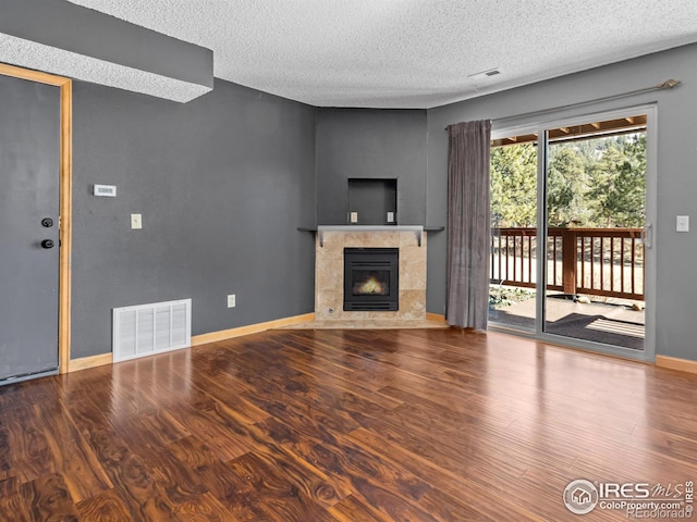 unfurnished living room featuring a tile fireplace, wood finished floors, visible vents, and baseboards