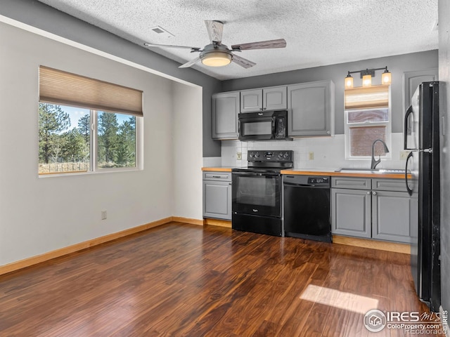 kitchen featuring black appliances, gray cabinets, and a sink