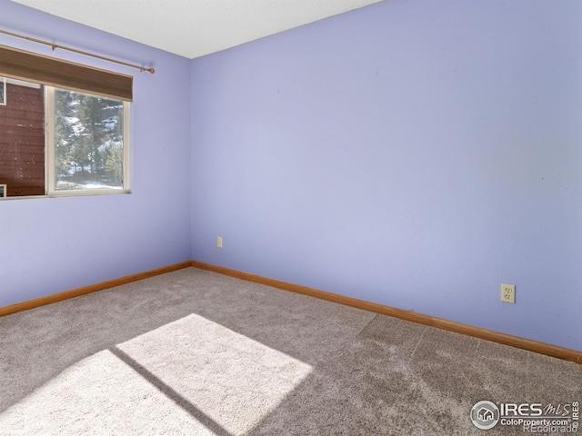 carpeted empty room featuring baseboards