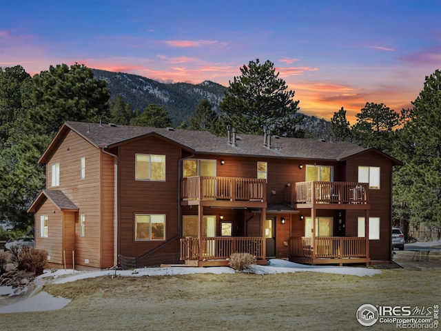 chalet / cabin with roof with shingles, a mountain view, and a balcony