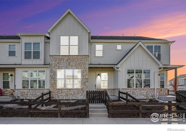 view of front of house featuring stone siding, board and batten siding, and fence