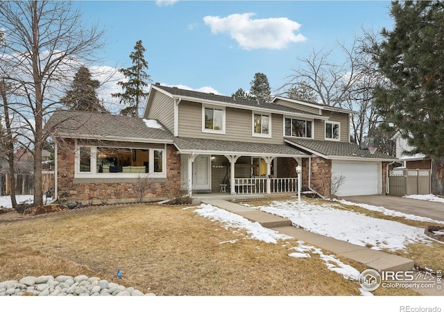 traditional-style home with driveway, stone siding, a porch, a yard, and a garage