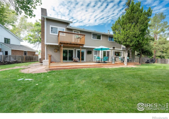 rear view of property with a lawn, a deck, a chimney, and fence