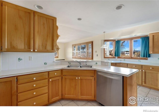 kitchen featuring a peninsula, light countertops, stainless steel dishwasher, a sink, and light tile patterned flooring