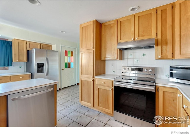 kitchen featuring under cabinet range hood, tasteful backsplash, stainless steel appliances, and light countertops