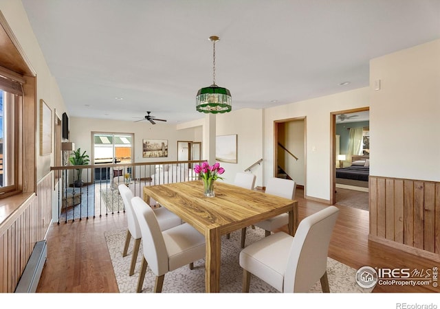 dining space with ceiling fan, wood finished floors, and wainscoting