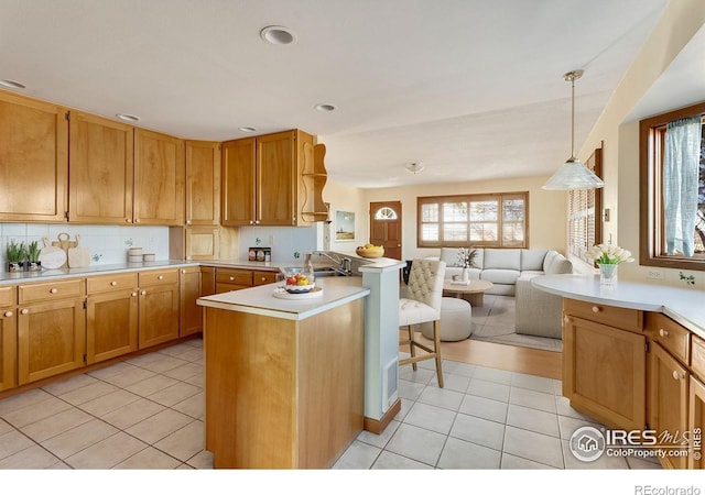 kitchen with tasteful backsplash, open floor plan, a peninsula, hanging light fixtures, and light countertops