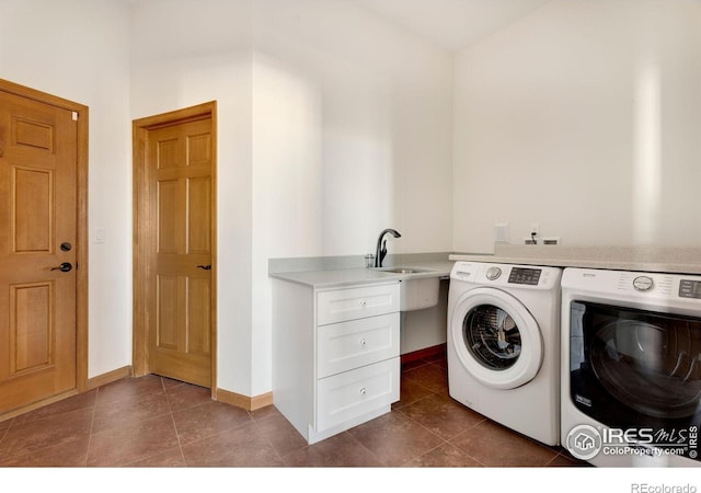 laundry area featuring laundry area, baseboards, dark tile patterned flooring, washer and dryer, and a sink