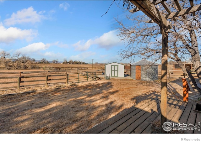 wooden deck with an outbuilding, a storage unit, a rural view, and fence