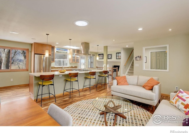 living area featuring light wood-style flooring, recessed lighting, stairway, and baseboards