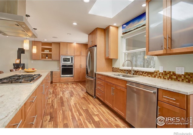 kitchen with island exhaust hood, open shelves, stainless steel appliances, a sink, and light stone countertops