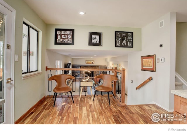 living area featuring light wood-type flooring, baseboards, stairs, and visible vents