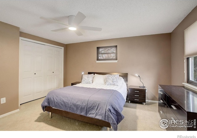 bedroom featuring a closet, light colored carpet, a textured ceiling, and baseboards