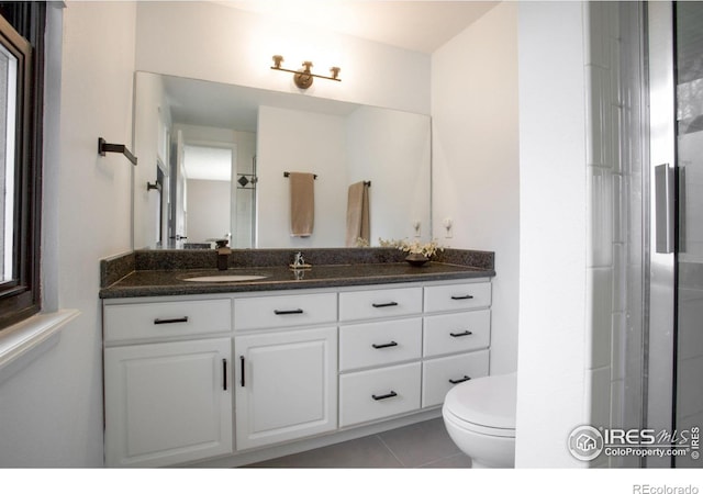 bathroom with toilet, vanity, and tile patterned floors