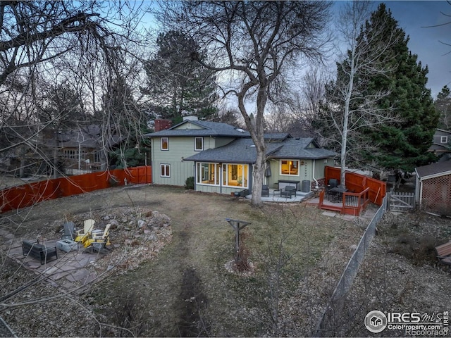 back of property with an outdoor fire pit, a shingled roof, a patio, a fenced backyard, and a deck