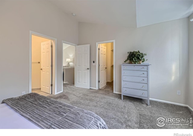 unfurnished bedroom featuring carpet floors, vaulted ceiling, baseboards, and a walk in closet