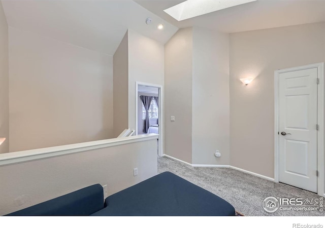 bedroom featuring carpet floors, lofted ceiling with skylight, and baseboards