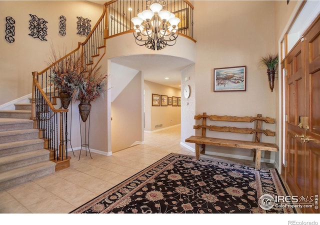 entryway featuring light tile patterned floors, baseboards, arched walkways, stairway, and a high ceiling