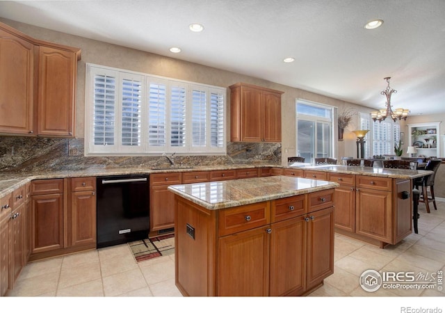 kitchen featuring dishwasher, a kitchen island, light stone counters, a notable chandelier, and a sink