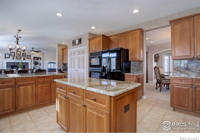 kitchen featuring black appliances, brown cabinetry, and light stone countertops