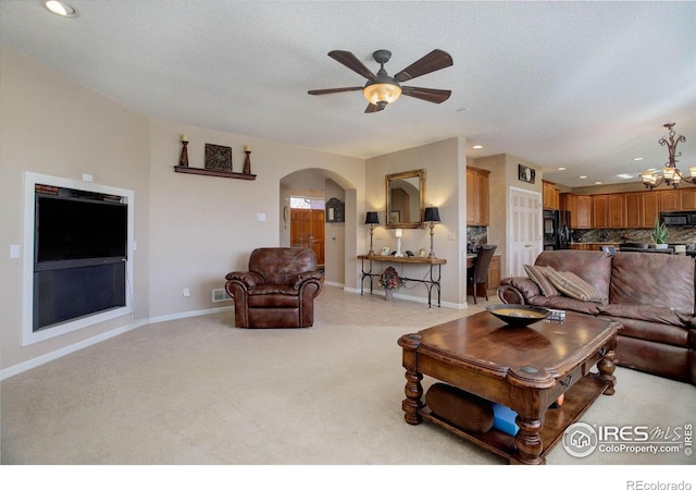 living area featuring arched walkways, recessed lighting, light carpet, baseboards, and ceiling fan with notable chandelier