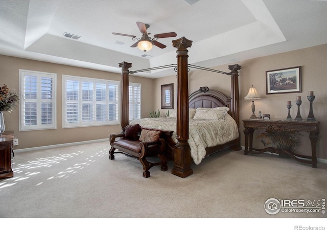 bedroom featuring carpet, visible vents, a raised ceiling, and baseboards