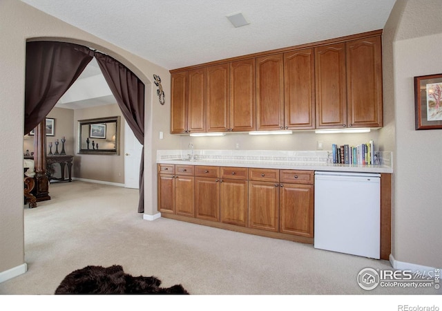 kitchen featuring light carpet, baseboards, dishwasher, brown cabinets, and light countertops